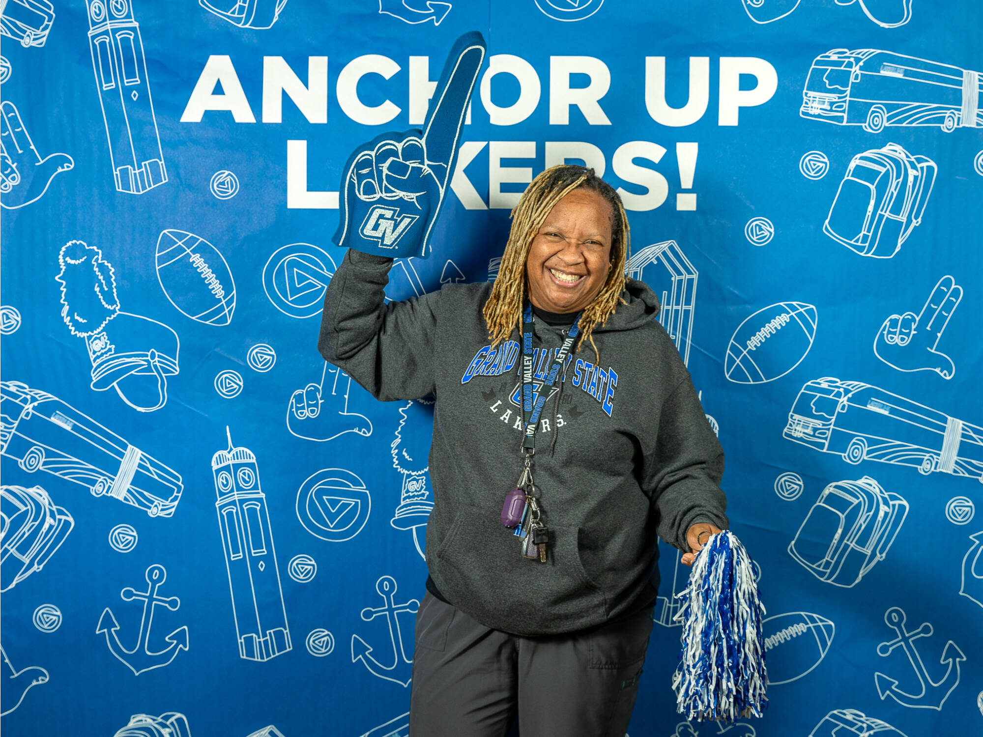 An individual holding up a GVSU foam finger and a blue and white pompom